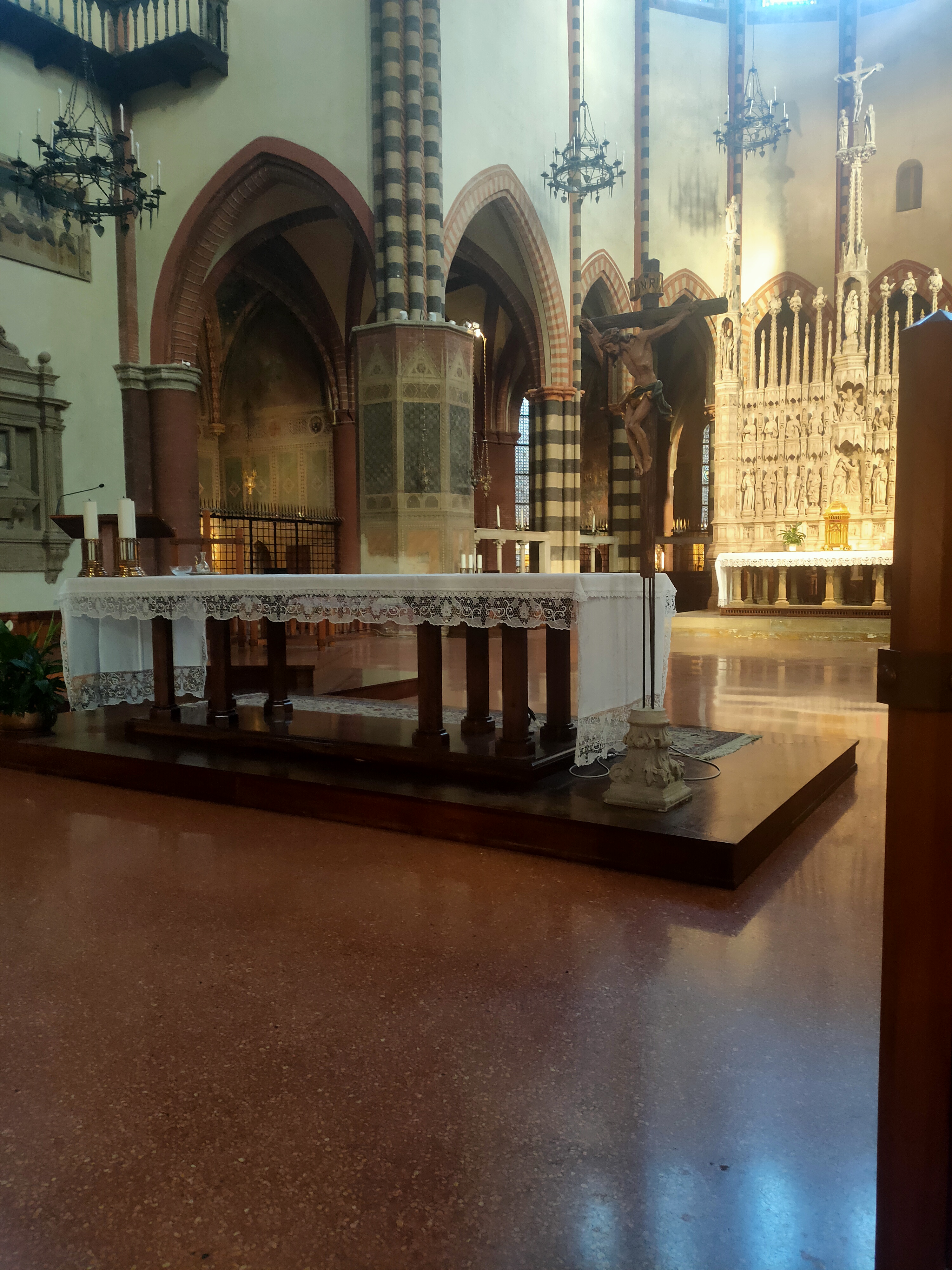 Altare e crocifisso in una chiesa, ripresi lateralmente tra archi e colonne