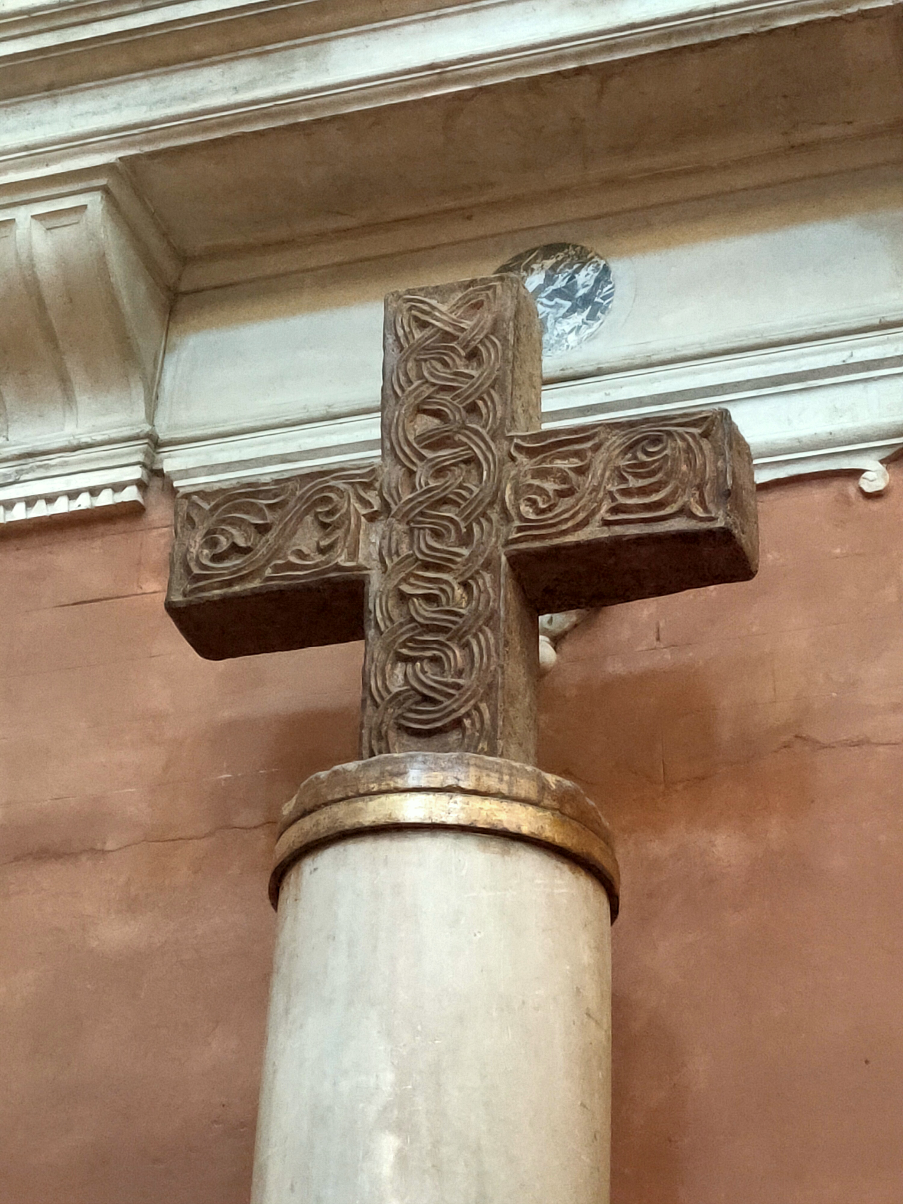 Croce in pietra con decorazioni intrecciate sopra una colonna chiara