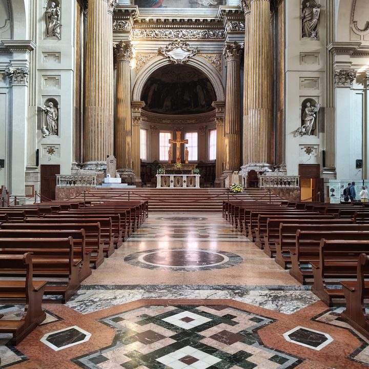 Navata della Cattedrale di San Pietro a Bologna: banchi, pavimento di marmo e, in fondo, l'altare con il crocifisso
