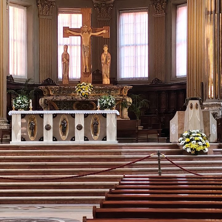 L'altare da vicino: il crocifisso con la Madonna e San Giovanni, le composizioni di fiori e il cesto davanti all'ambone